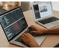 A person typing on a computer, with another computer beside them. 