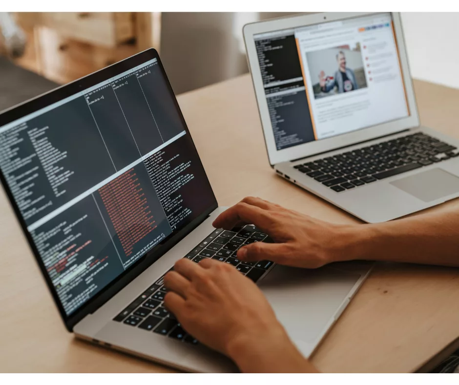 A person typing on a computer, with another computer beside them. 