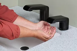 A person using an automatic soap dispenser. 