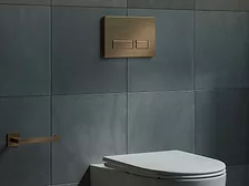 A bronze Wall Flush Plates from California Faucets on a bathroom wall. 