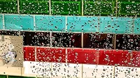 Droplets of water on a glass shower screen with colorful horizontal subway tiles in the background.