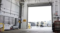 The interior of a warehouse, with a view of the outside.