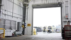 The interior of a warehouse, with a view of the outside.