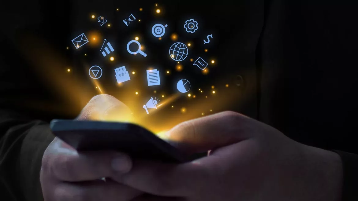 Marketing Matters Column. Hands holding a mobile phone with glowing social media icons floating out of phone.