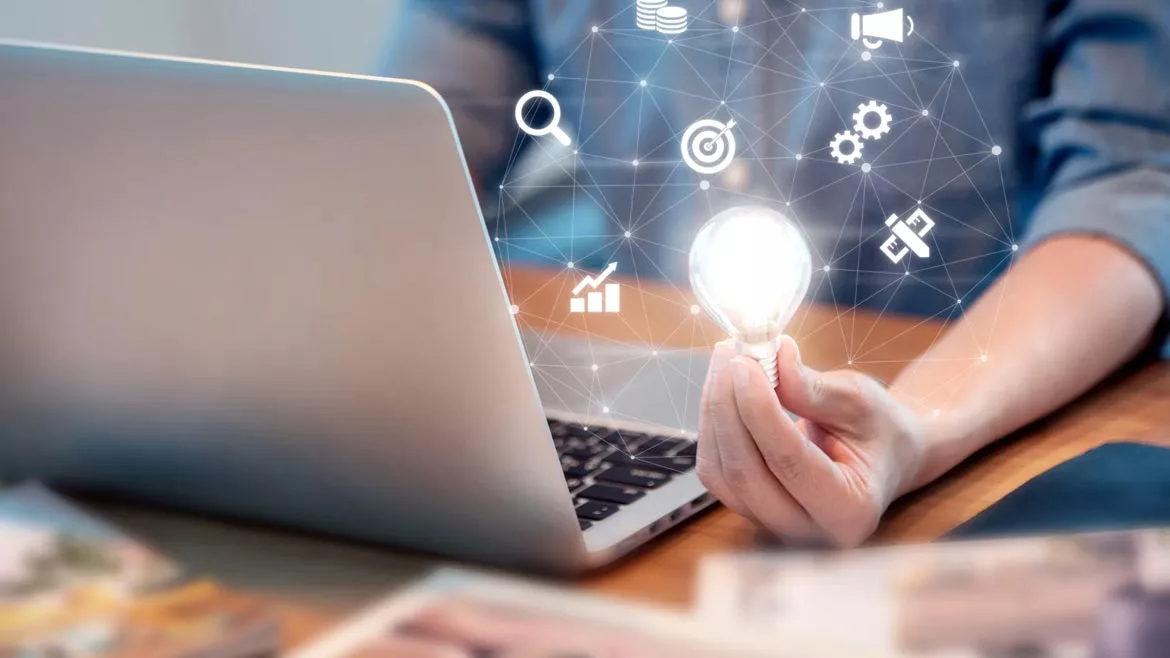 Jeff Valles column feature image of man on laptop holding a lightbulb with small icons floating around it.