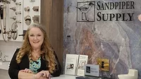 Sandpiper Supply Remodel feature image of Christy Ellis, showroom director, standing next to sign and brochures.