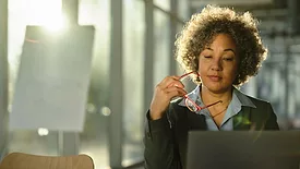 SHT March 2024 Women in Industry feature image woman holding red glasses working on her laptop.