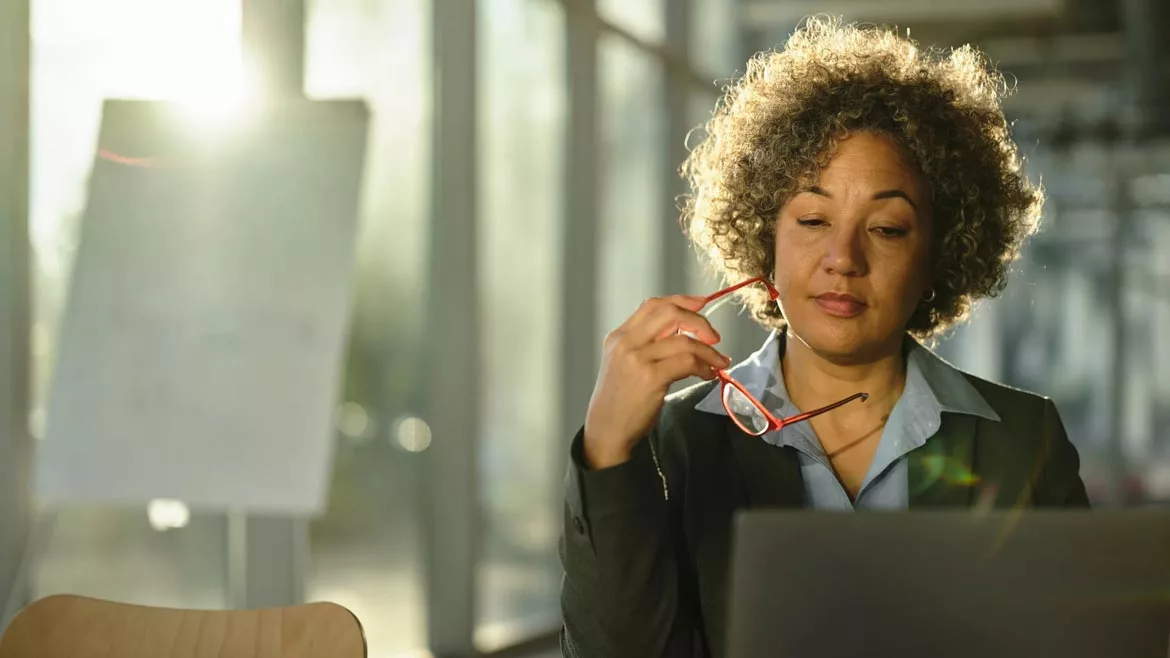 SHT March 2024 Women in Industry feature image woman holding red glasses working on her laptop.