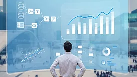 Man standing in front of giant computer screen with charts and diagrams