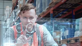 Warehouse worker using a large transparent computer touchscreen.