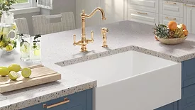 Kitchen island with a farmhouse sink and brass faucets.