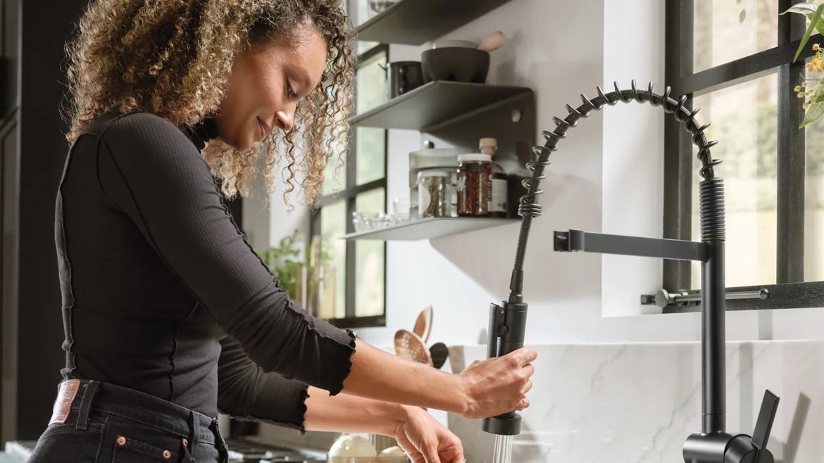 Woman washing a cutting board in the sink.