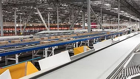 A large warehouse with multiple conveyor systems moving boxes and packages.