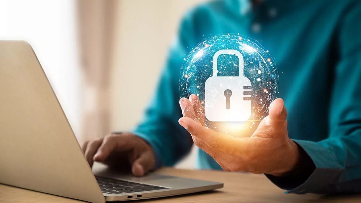 Lock icon and internet network security technology bubble floating above the hand of person using a laptop.