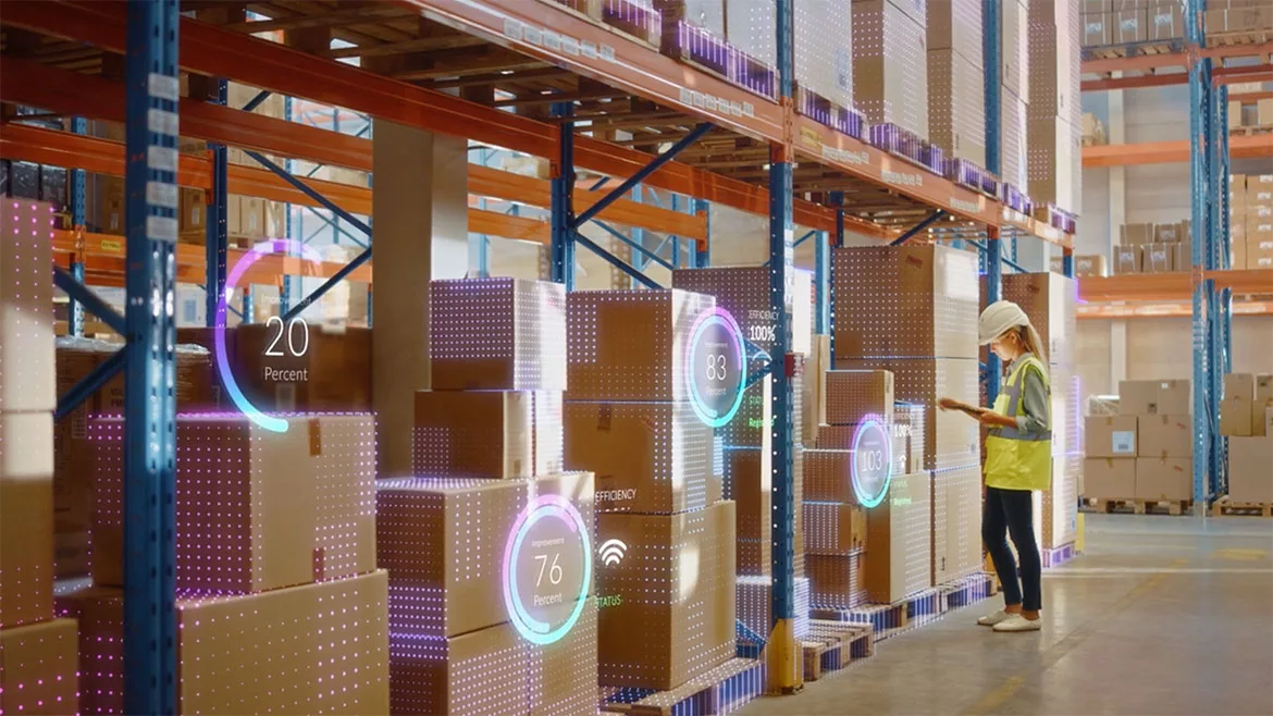 Retail warehouse worker in a safety vest and hard hat, scans inventory using a barcode scanner. A virtual infographics is displayed on the boxes.