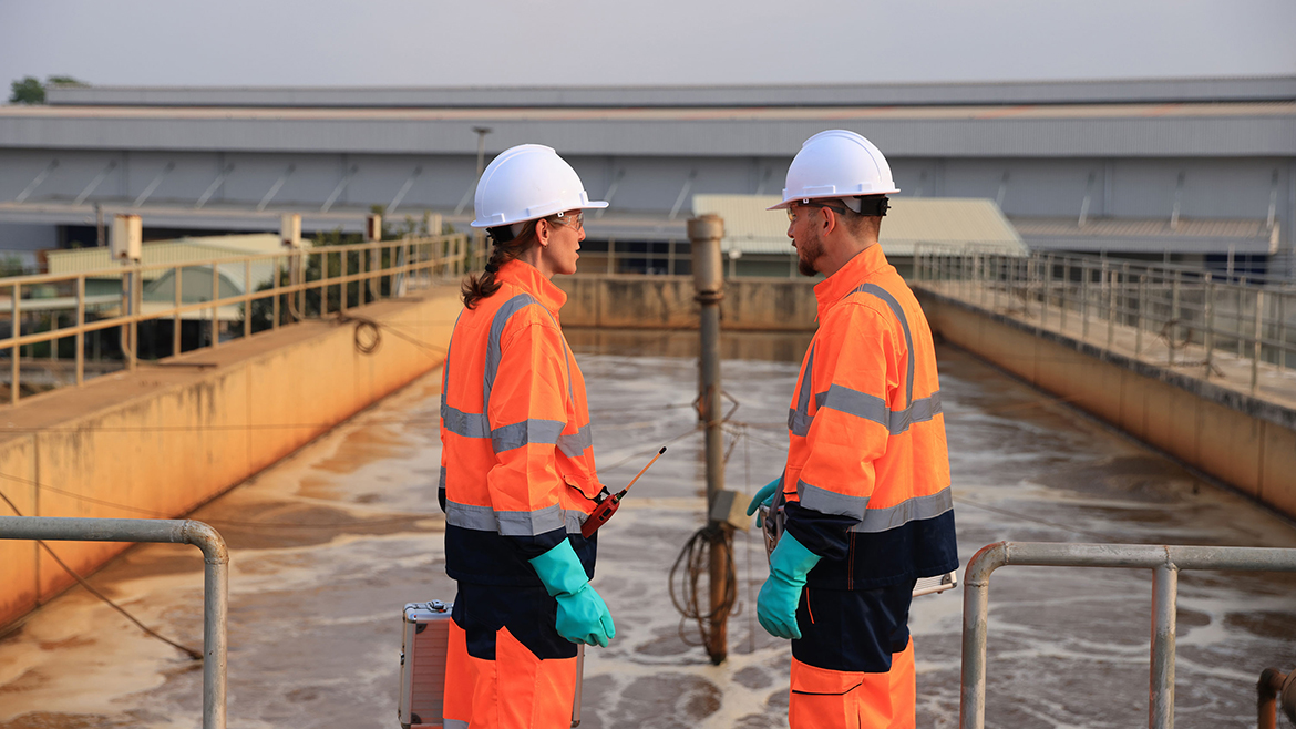 Two safety and environmental engineers working at a wastewater treatment plant checking the quality of the water.