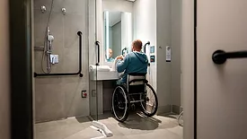 Mature man in a wheelchair drying his hands in the bathroom.