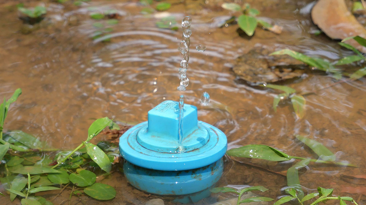 Broken water pipe on the ground with water overflowing.