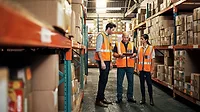 Warehouse employees talking, one holding a tablet Warehouse employees talking, one holding a tablet for logistics, shipping and distribution.