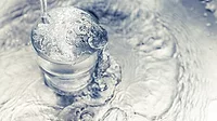 Pouring water from tap to glass on stainless steel.