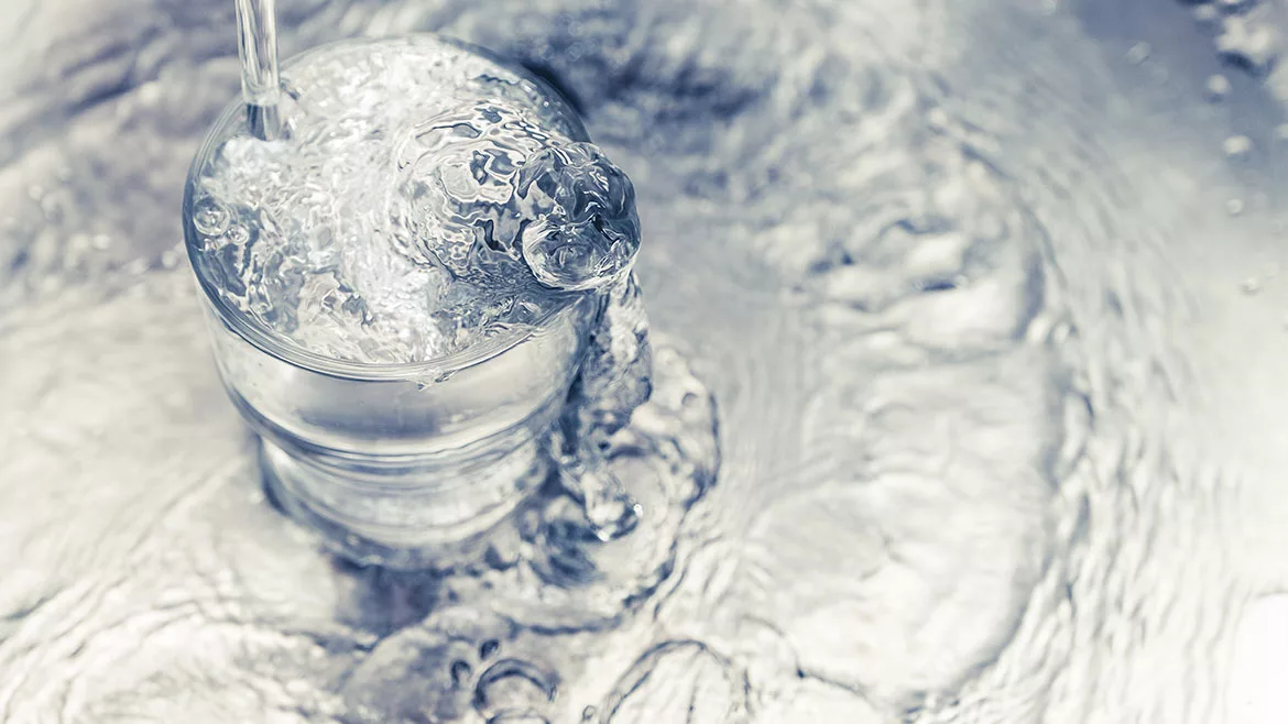 Pouring water from tap to glass on stainless steel.