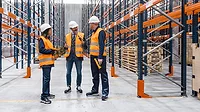 Warehouse workers and manager discussing logistics and planning inside a storage facility.