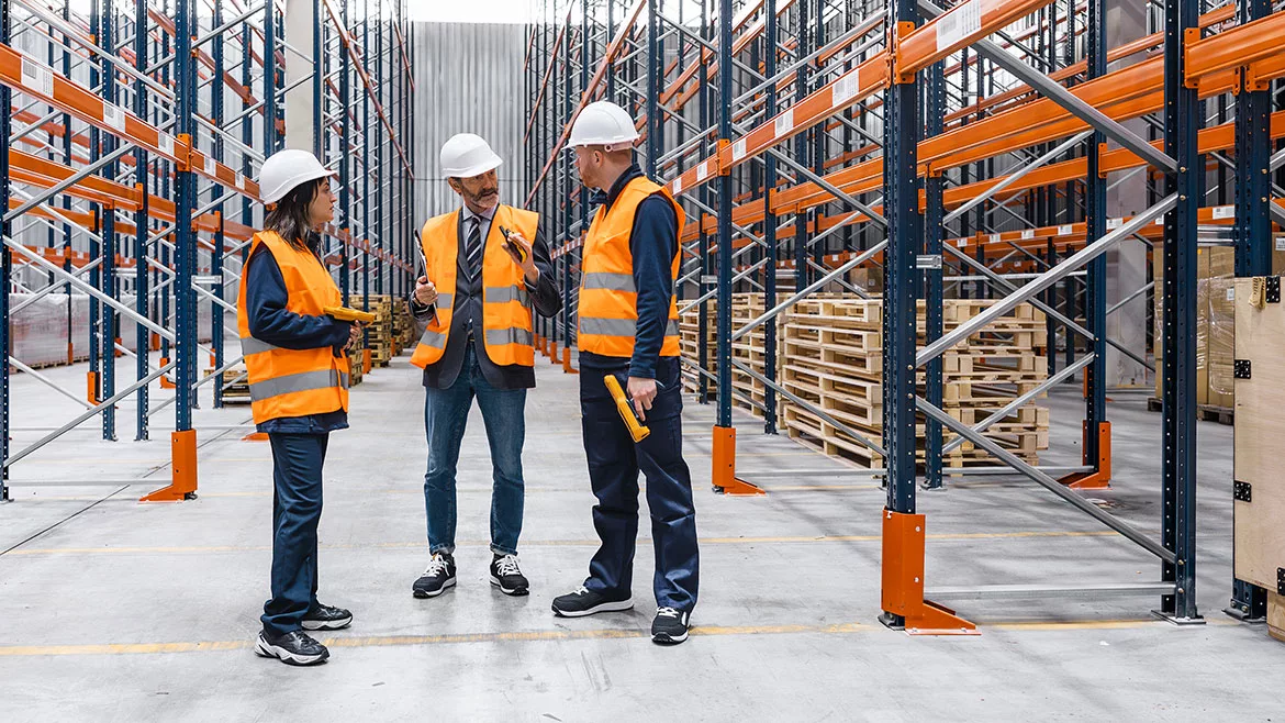 Warehouse workers and manager discussing logistics and planning inside a storage facility.