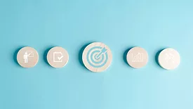 Round wooden blocks with business target objective icons on a light blue background.