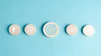Round wooden blocks with business target objective icons on a light blue background.