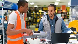 Salesman helping a customer buy a toolbox at a hardware store.