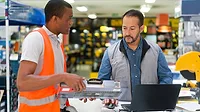 Salesman helping a customer buy a toolbox at a hardware store.