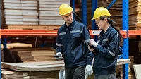 Young employee checking stock In a large cardboard factory.