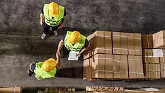 High angle view of two workers shaking hands while working with their colleague in distribution warehouse.