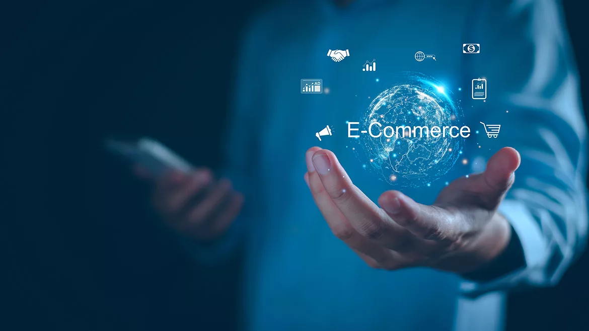 A cropped image of a man holding a glowing digital globe in his hand, with “E-Commerce” text and business icons against a blue background.