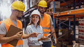 A female manager, along with two warehouse workers, is inspecting the merchandise.