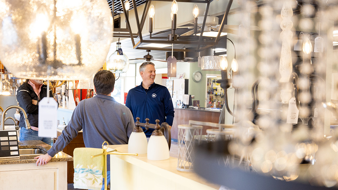 White Star Supply showroom representative smiling while talking with customers in the light and home decor section.