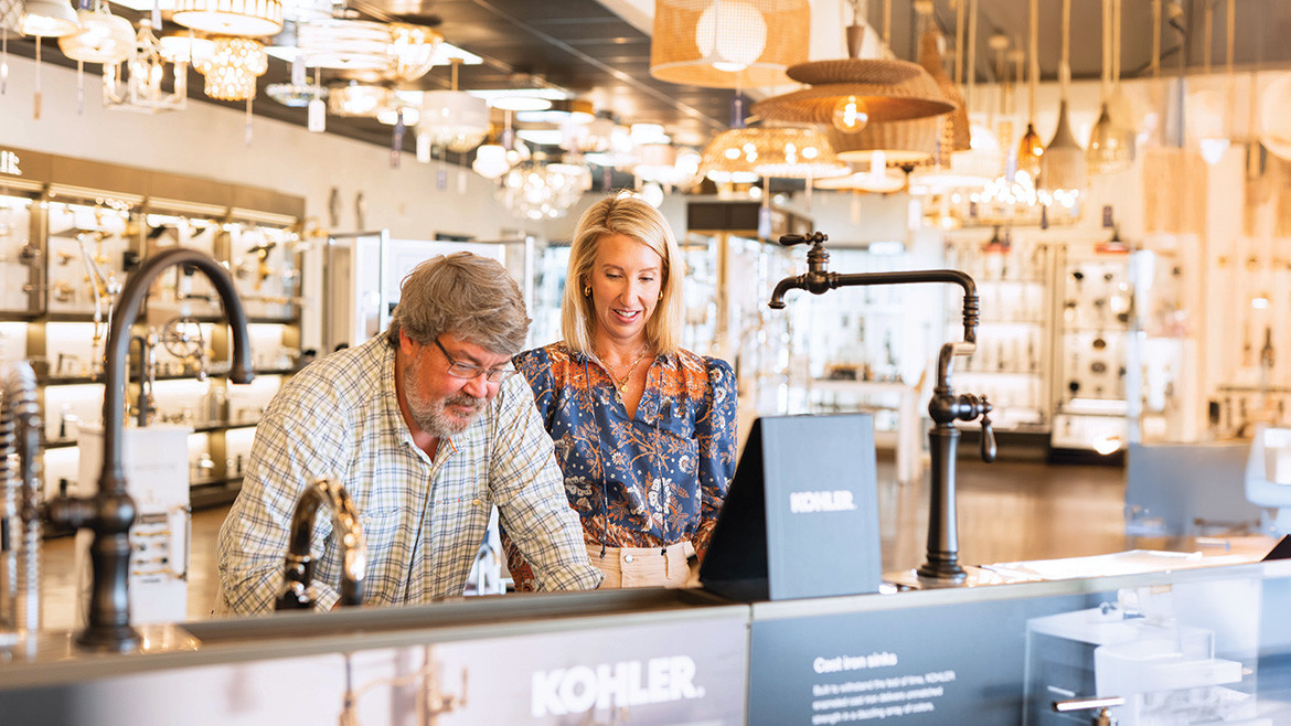 A man and a woman looking at faucets and sinks in a Kohler showroom.
